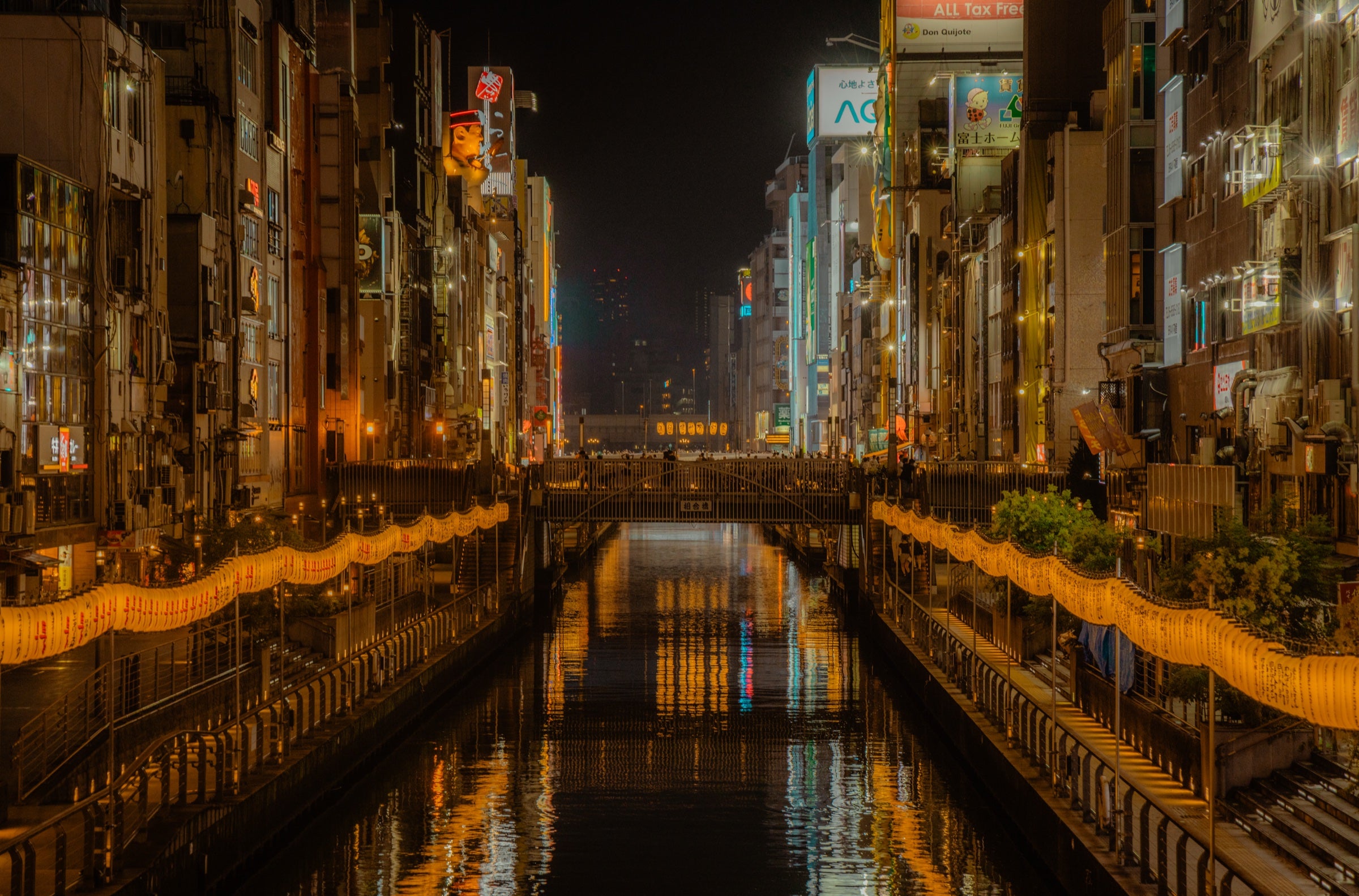 Canal bordé d'enseignes lumineuses la nuit à Osaka